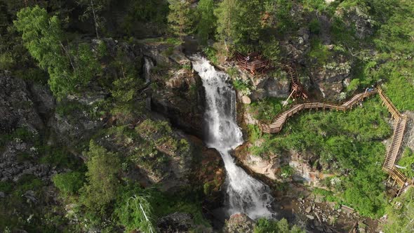 Drone Flying Over a Green Forest with Waterfall in the Altai Mountains.