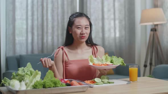 Smiling Asian Woman Enjoys Eating Healthy Food And Looking At Camera At Home alt