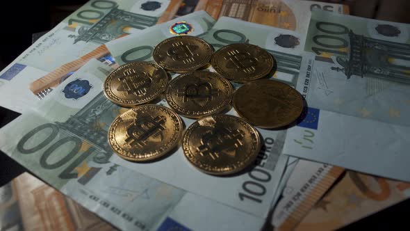 Bitcoin BTC coin rotating on bills of 100 and 50 euro. Digital coin cyberspace and cryptocurrency. C alt