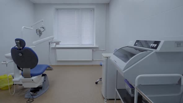 Empty Dentistry Room Equipped with Blue Dental Unit Furniture Operating Lamp