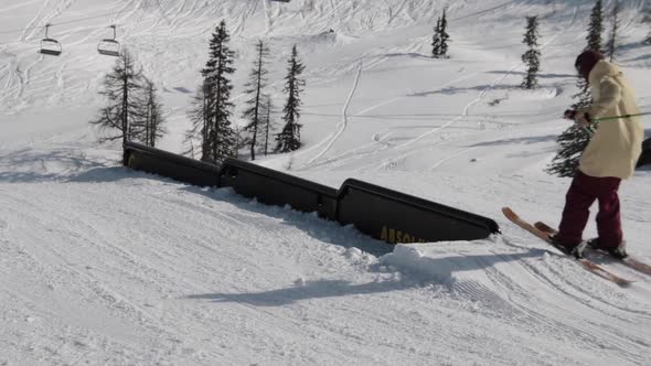 A young man skier performing grind tricks in terrain park. alt