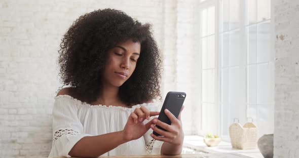 A Happy Young Black African Woman Spending Time at Home Using Her Cell Phone alt