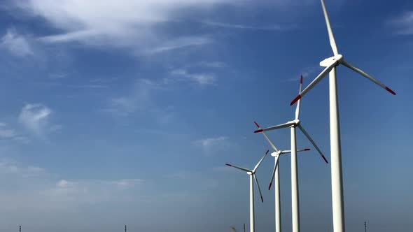 Giant wind turbines with three blades with the sky and clouds in the background producing clean ener alt