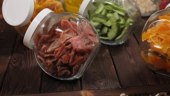 Glass Jars with Various Dried Fruits on a Brown Wooden Background alt