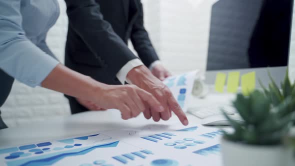 Two business people analysing and looking at diagrams on documents in workplace