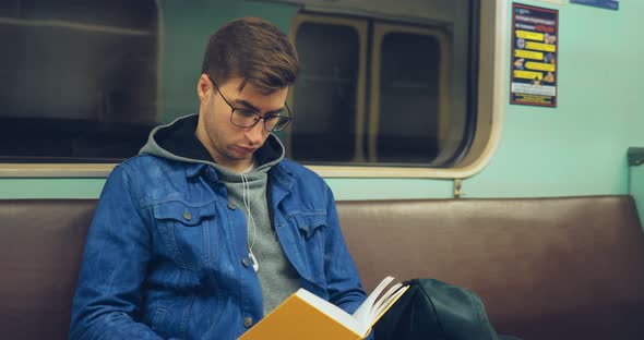 Brutal Guy with Glasses Riding in a Subway Car and Reading a Book with Interest alt