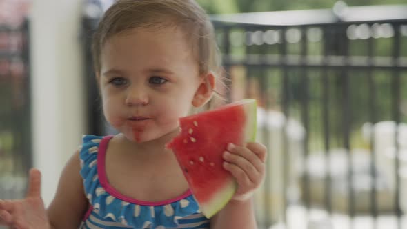 Young girl eating watermelon at backyard barbeque