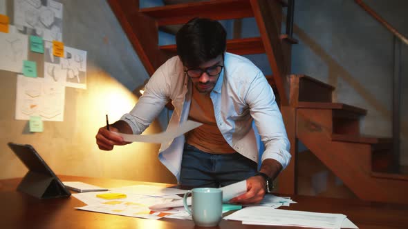 Businessman in casual Clothes checking and analyzing financial business paperwork in office at night