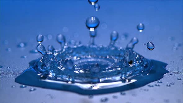 700670 Drop of Water falling into Water against Blue background, Slow motion alt