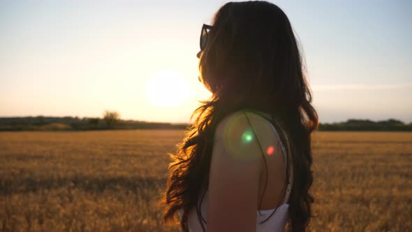 Beautiful Woman Walking Through Field of Wheat at Sunset. Profile of Carefree Girl Enjoying Summer alt