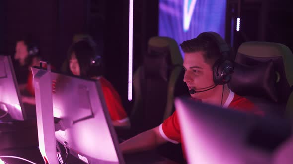 Handheld Focused Gamers in Headphones Plays a Video Game Cyber Sportsman Communicates with the Team alt