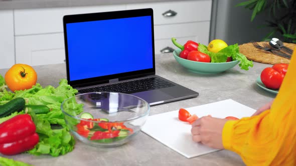 Blue Screen Laptop Woman Housewife in Kitchen Slices Tomato Listen Tells Chef alt