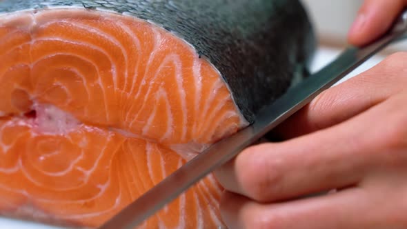 Male Chef Cuts Slicing a Fresh Salmon Fillet in the Sushi Bar Restaurant alt