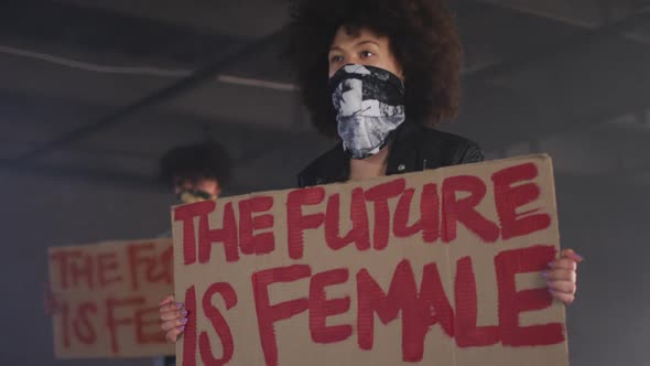 Mixed race man and woman wearing face masks holding protest signs alt