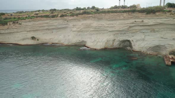 AERIAL: Limestone Wall of Ta Kalanka Sea Cave Bay Washed with Turquoise Color Sea alt