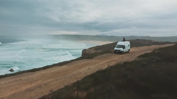 Landscape of wild ocean coast with waves and a van shot by drone alt