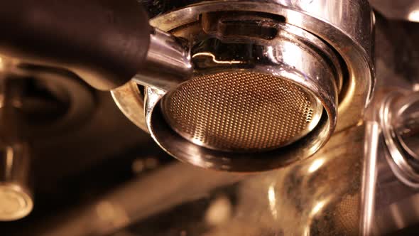 Closeup of pouring coffee stream from professional machine through the bottomless portafilter type alt