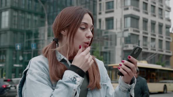 Winner Smiling Young Woman in Jean Jacket Looking at His Smartphone Screen and Celebrate Good News alt