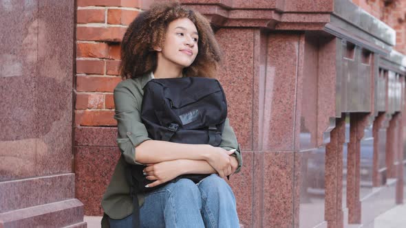 Young Attractive African American Girl with Curly Hair Wearing Jeans and Sneakers Holding Travel alt