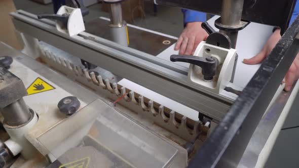 A drilling machine makes a hole in a wooden slab. hand of man alt