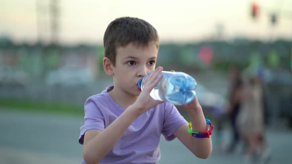Tired Schoolboy Drinks Fresh Drinking Water From a Plastic Bottle
