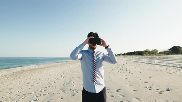 Business Man in Blue Shirt Wears Virtual Reality Glasses at the Beach alt