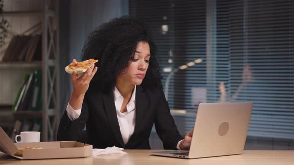 Portrait of African American Woman Eating Pizza and Working on Laptop alt