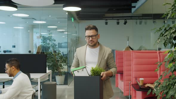 Fired Middle-aged Man in Suit Is Walking in Shared Office Leaving Workplace with Box alt