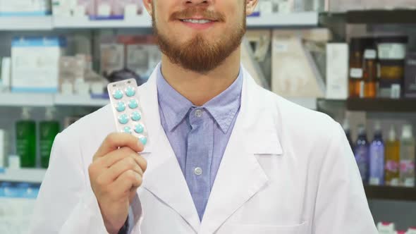 The Pharmacist Holds Pills in His Hands and Shows a Thumbs Up