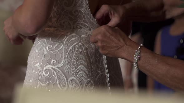 Elderly hands of mother fasten buttons on bride's back wedding dress. Luxury Marriage Accessories