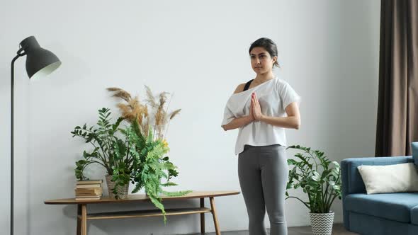 Young Indian Woman Meditating Standing on Carpet and hand Namaste, Doing balance alt