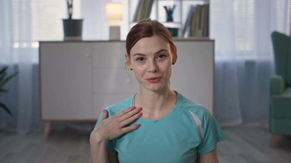 Woman in Sports Clothing Communicates Via Video Communication on Laptop and Shows Bottle of Clean