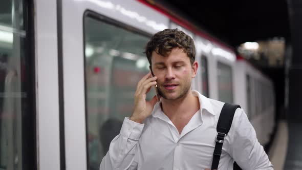 Businessman Talking on Cellphone Near Train alt
