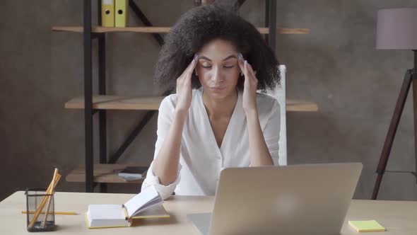 Tired Stressed Mixed Race Woman Sitting at Table Near Laptop Touch Massaging Temples Suffers  alt
