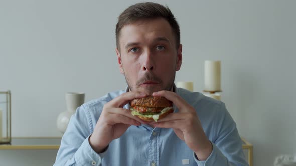Young Man Holding a Piece of Hamburger alt
