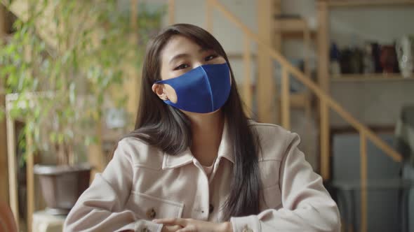 A Young Woman in Facial Protective Mask is Looking to the Camera alt