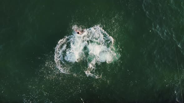Aerial Top View of Group of Young Friends Jumping From a Pier Into the Sea During Beautiful Sunrise alt