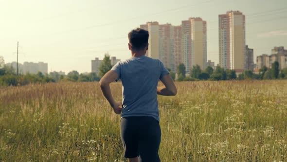 Running Man On Green Grass Field.Slow Motion Running Man Exercising On Trail.Man Running On Park alt