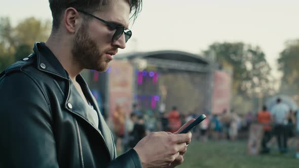 Young caucasian man on music festival using phone. Shot with RED helium camera in 8K. alt