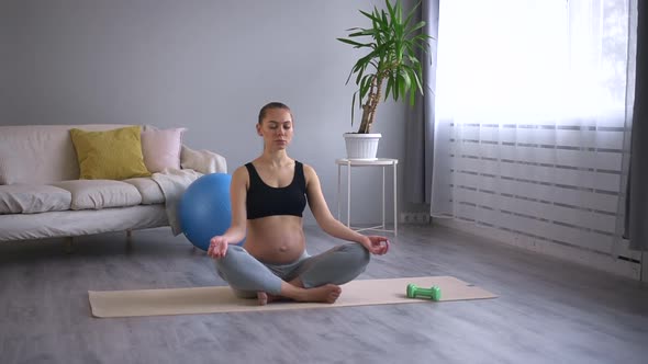 Pregnant Woman Doing Asana and Practicing Yoga on Floor in Home Room Spbd alt