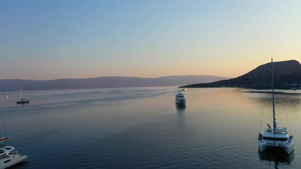 Catamaran and Sail Yachts Anchored at Bay on Deep Blue Sea Water on Sunrise alt