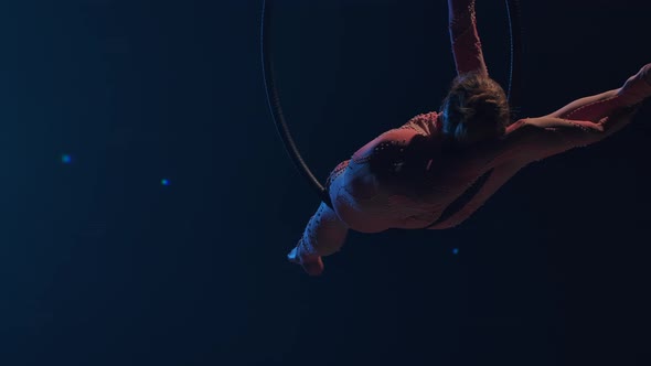 A Young Woman Gymnast Performs Acrobatic Stunts on an Air Hoop Under the Dome of a Circus and alt