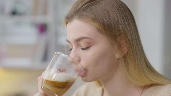 Headshot of Charming Confident Caucasian Young Woman Drinking Cappuccino and Smiling alt