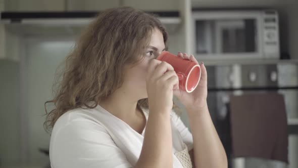 Close-up of Plump Brunette Woman with Brown Eyes Drinking Coffee and Smiling at Camera. Portrait of alt