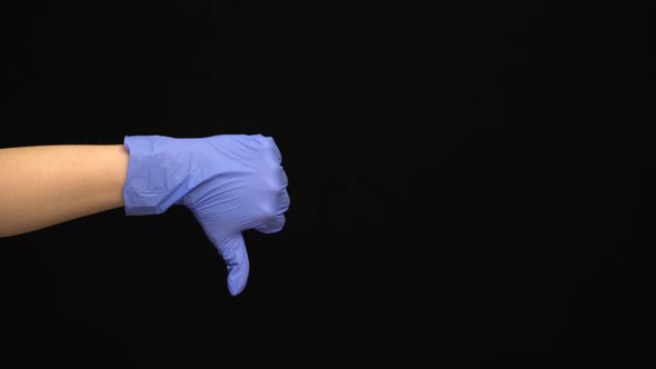 Female Hand in a Latex Medical Glove Makes an Unlike Gesture Isolated on Black Background alt
