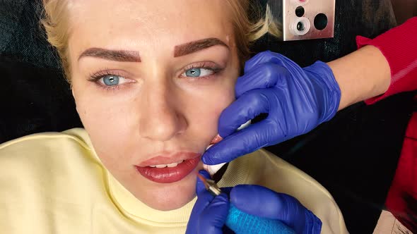 Permanent Makeup Lips Procedure Applying Pigment Makeup on Lips with a Tattoo Machine Close Up