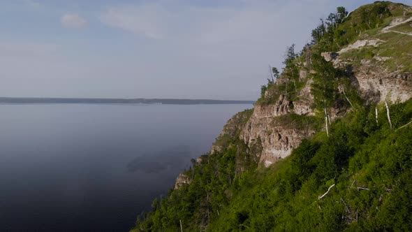 Flight Along a Picturesque Cliff Above the River. A Huge Reservoir and a Steep Stone Cliff. alt
