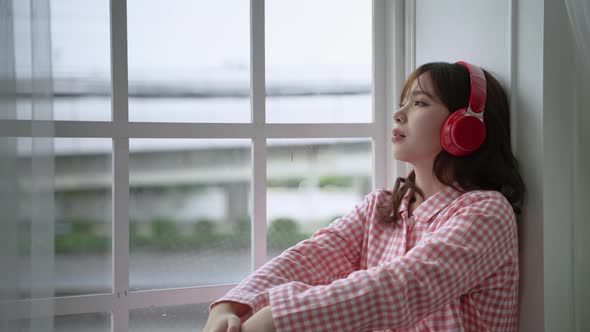 Asian girl sitting lonely listening to music in the window,