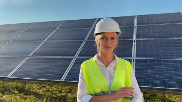 Portrait of Beautiful Female Engineer Technologist Standing Among Solar Panels with Her Arms Crossed