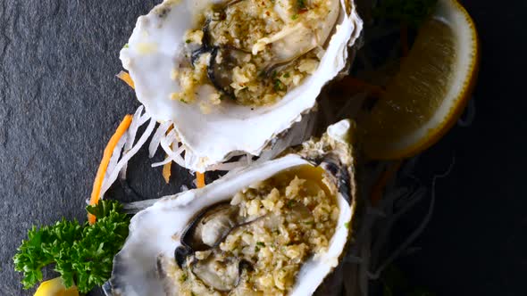 Fresh Raw Oysters in Shells with Lemon on Black Textured Slate Stone Top View